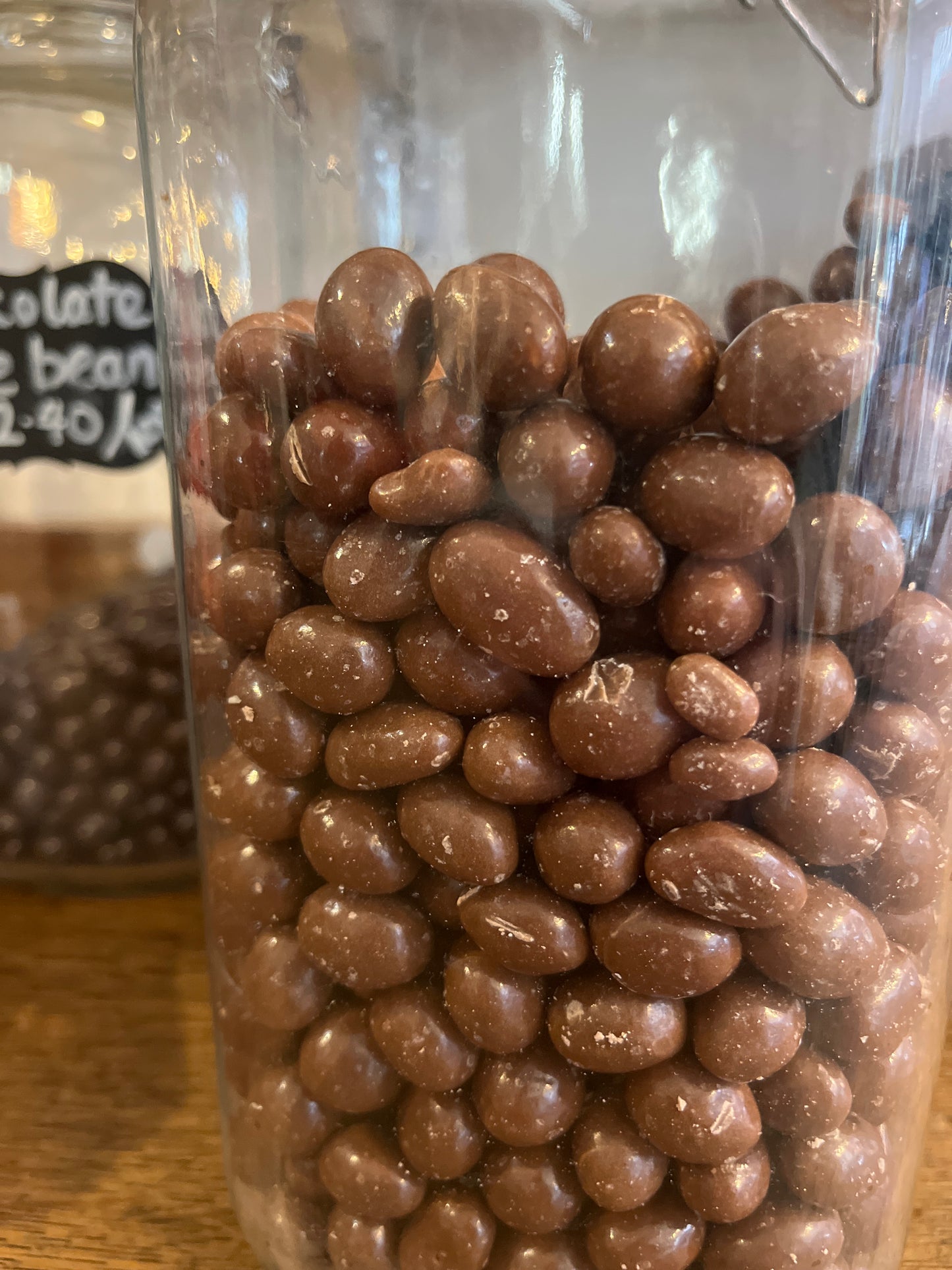 A jar filled with chocolate coated peanuts seen from the side.