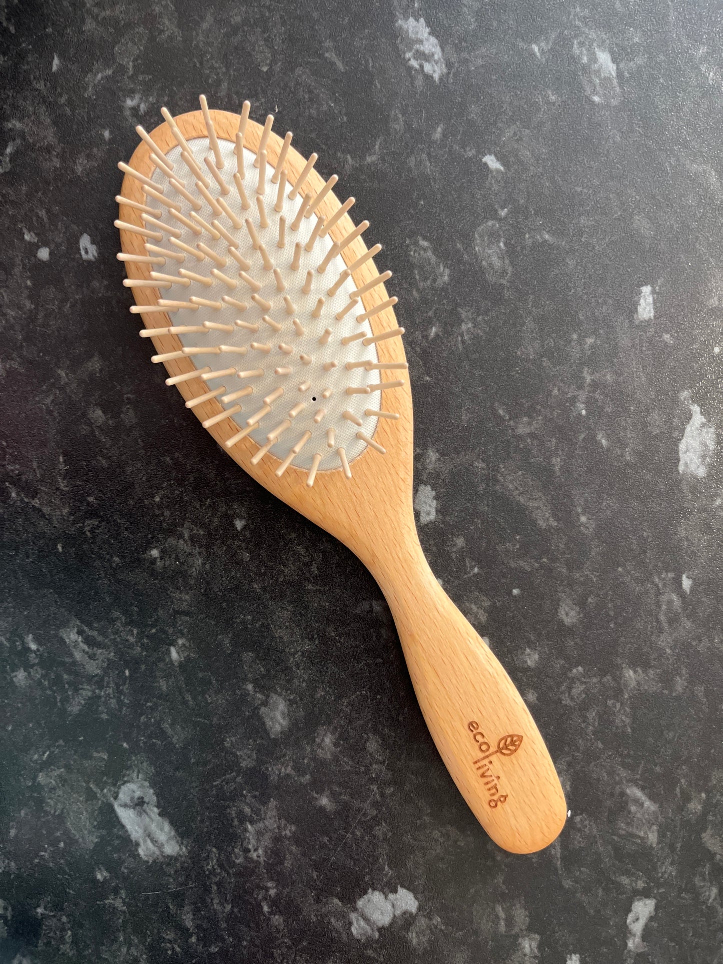 A plastic free hair brush made from bamboo with a white rubber cushion and rounded hornbeam pins.