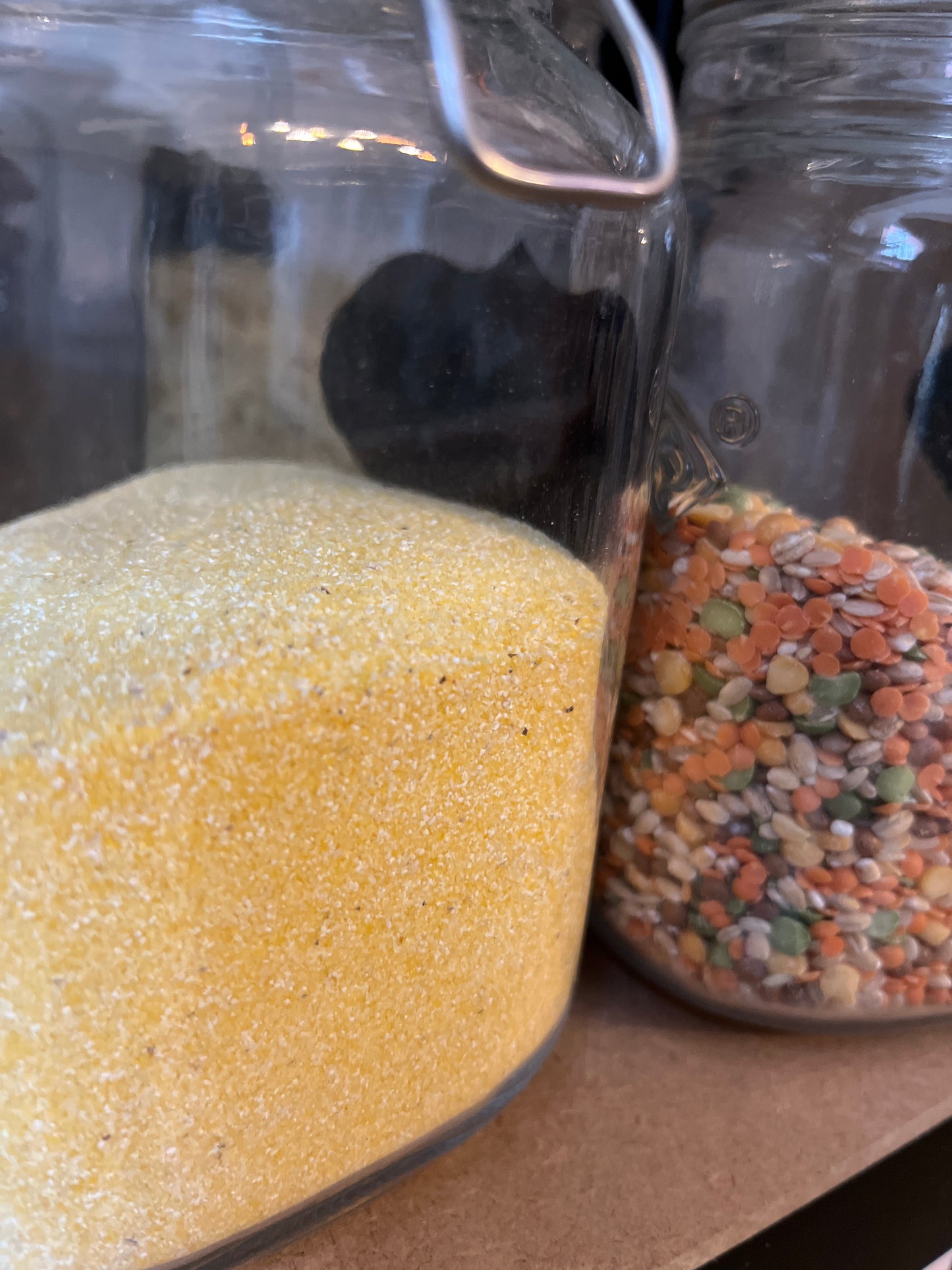 Two jars hold fine yellow grains of polenta and varied colourful dried lentils and grains in a soup mix.