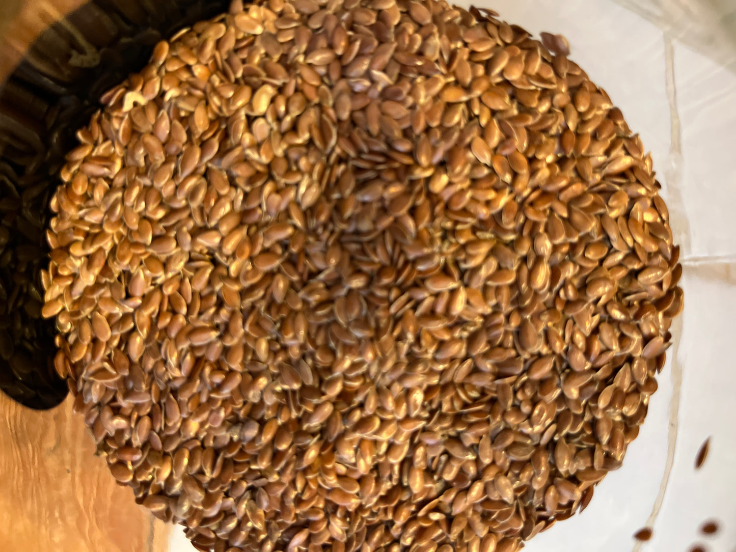 Looking down into an open jar of whole shiny brown linseed (or flaxseed).