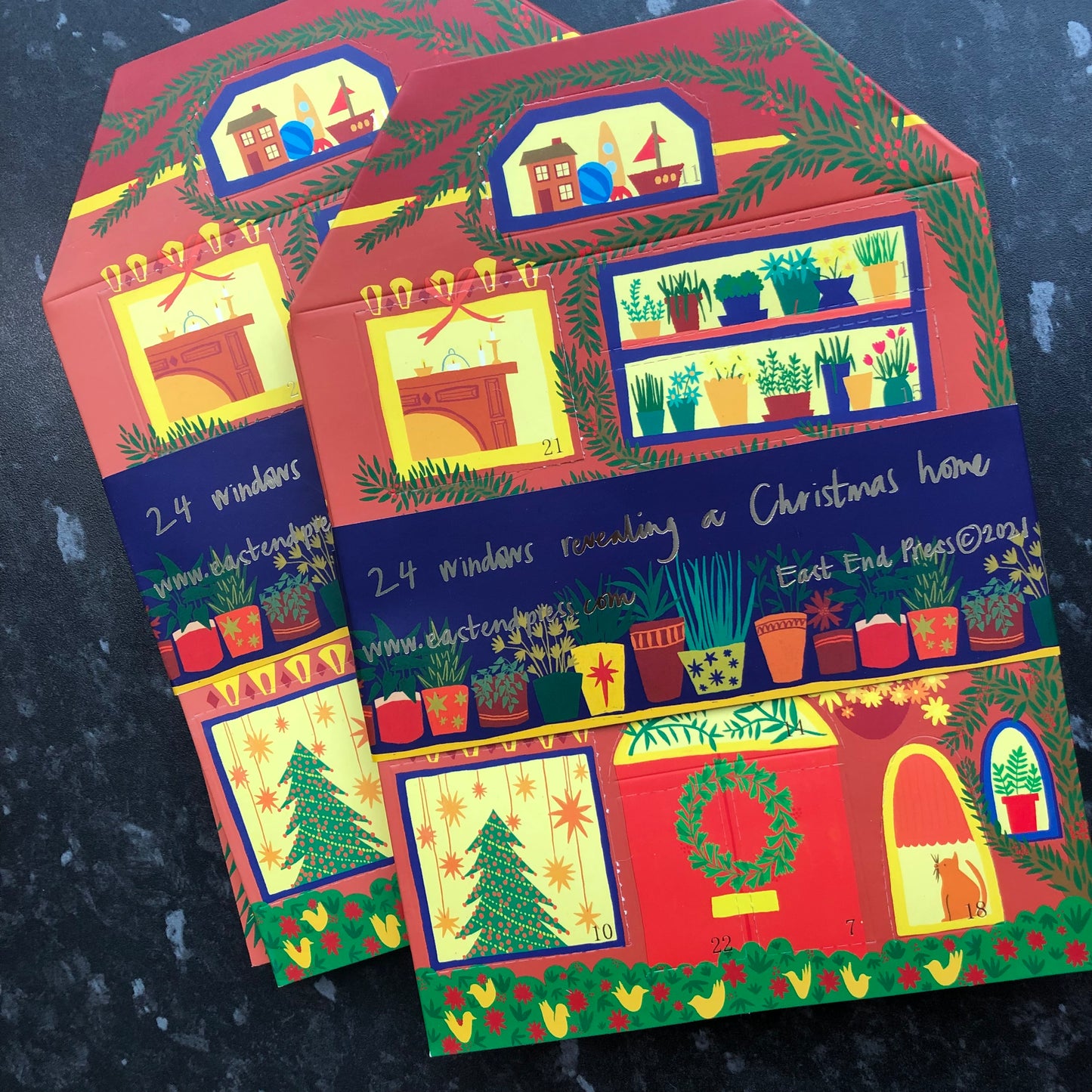 Two of the house shaped advent calendars lay on a marble counter.