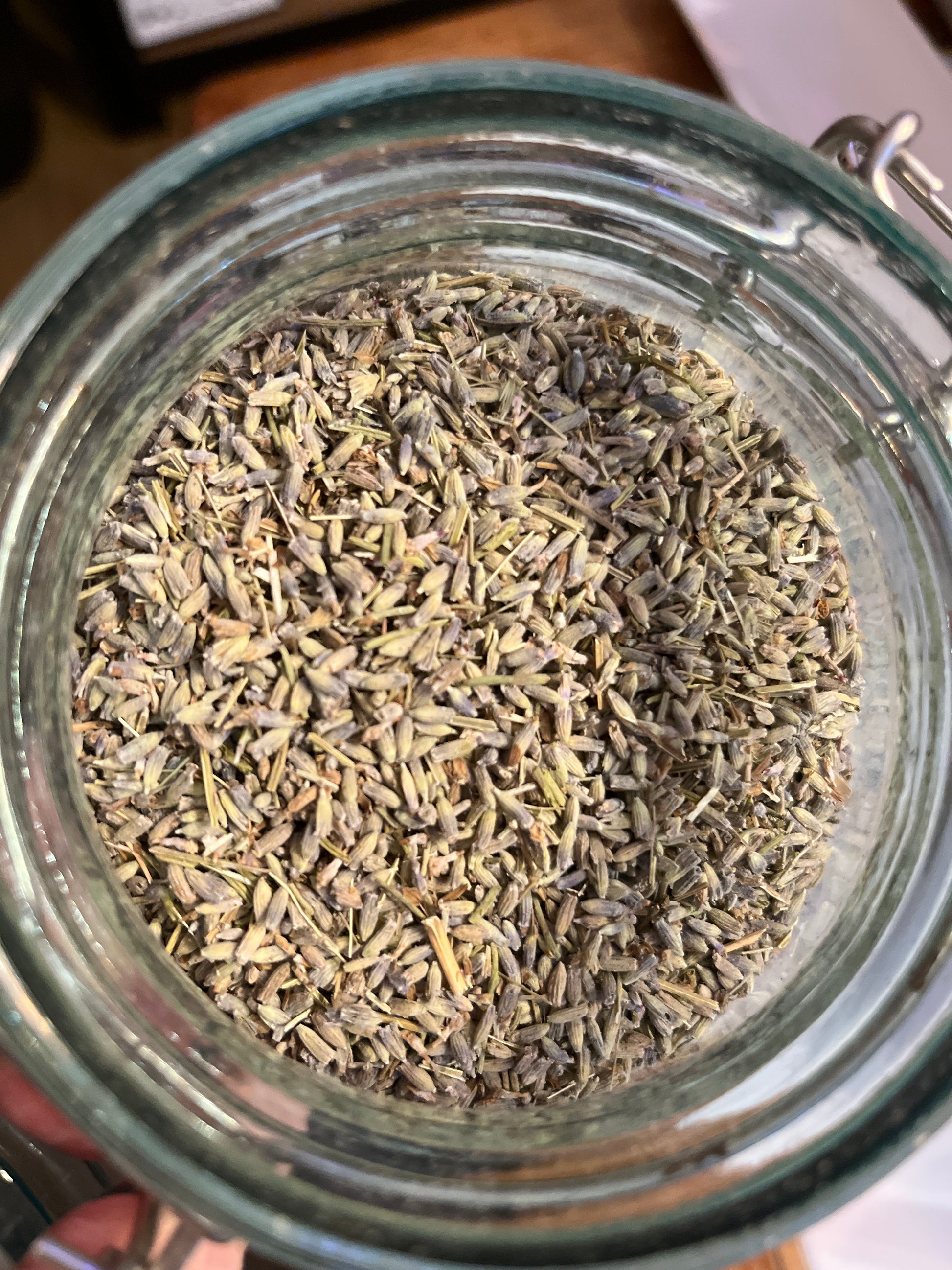 Dried lavender is shown in an open aqua coloured glass jar.