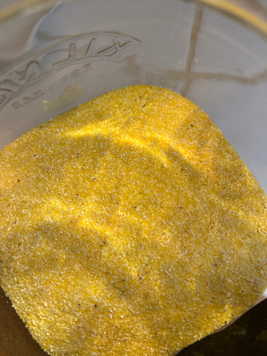 A rich golden yellow finely grained cornmeal for making polenta is shown in a glass jar.