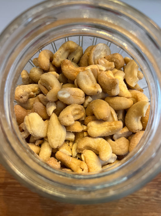 An open jar of roasted salted shelled cashew nuts viewed top down.