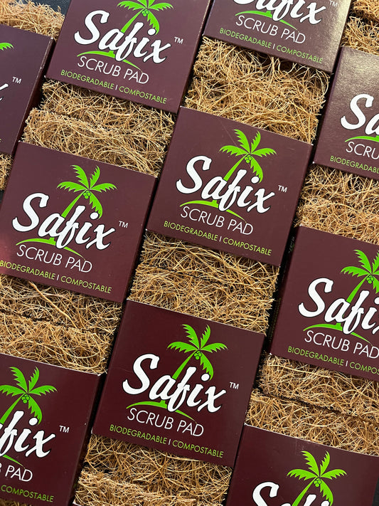 A slanted layout of lots of coconut scrub pads or scourers. They have a brown card sleeve with a green palm tree with 'Safix scrub pad. Biodegradable. Compostable' printed in white and green.