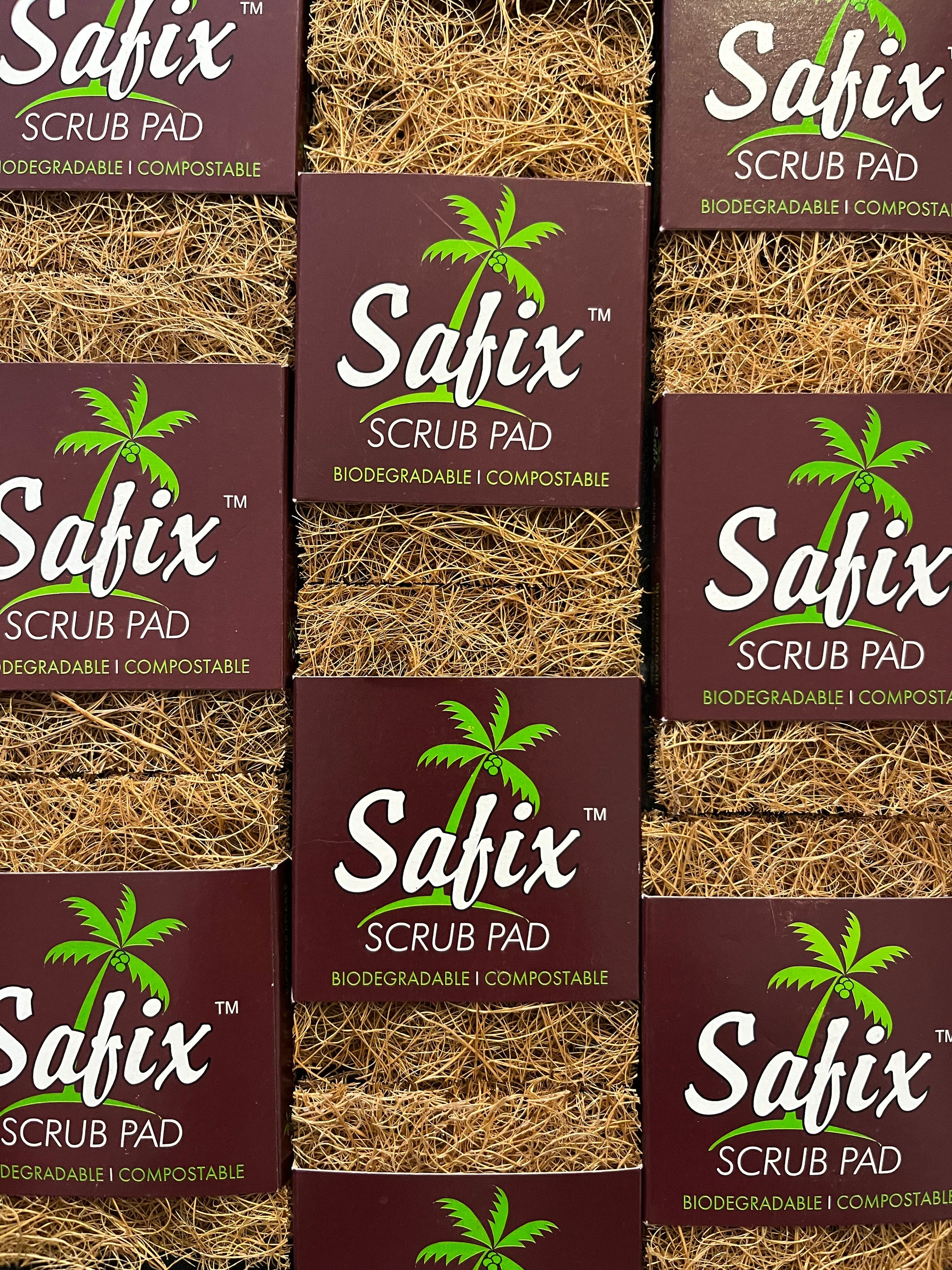 A layout of lots of coconut scrub pads or scourers. They have a brown card sleeve with a green palm tree with 'Safix scrub pad. Biodegradable. Compostable' printed in white and green.