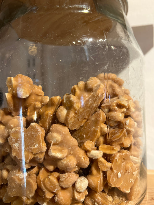 Delicious golden brown peanut clusters half fill a large jar.