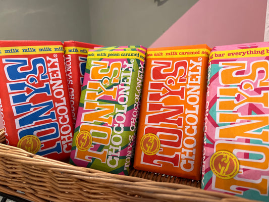 A row of brightly coloured wrapped Tony’s Chocolonely chocolate bars in a display basket