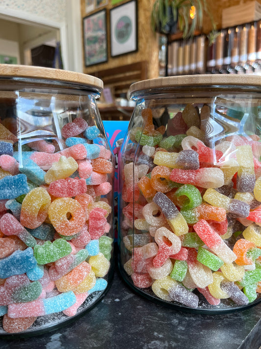 Two big jars filled with colourful fizzy vegan gummy sweets in a zero waste shop.