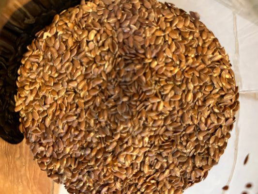 Looking down into an open jar of whole shiny brown linseed (or flaxseed).